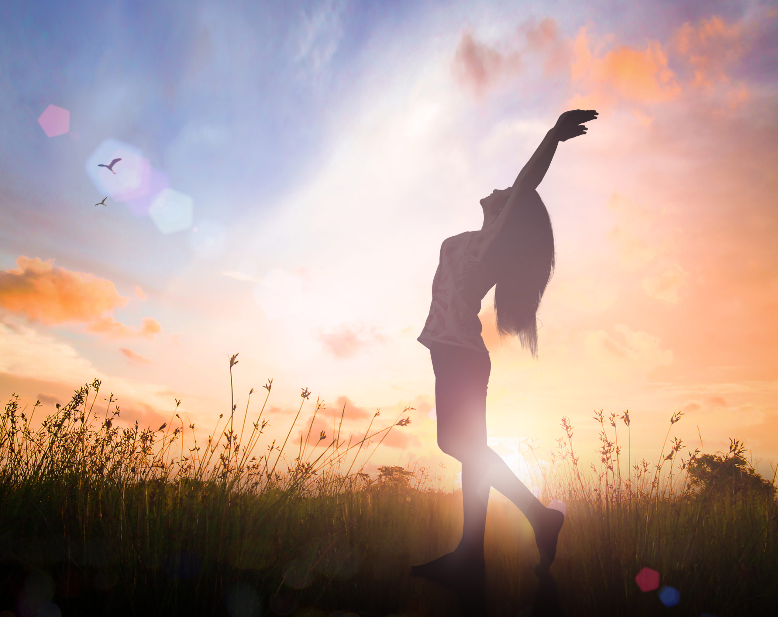 Silhouette of healthy woman raised hands for praise and worship God at autumn sunset meadow background