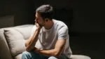 Depressed young man lost in his thoughts sitting on psychiatric examination bad. Life after divorce. Sad man after being fired