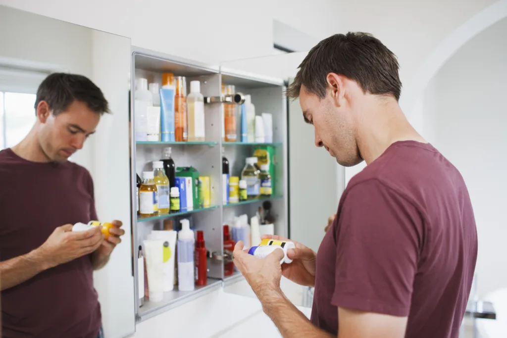 Man looking at bottles from medicine cabinet